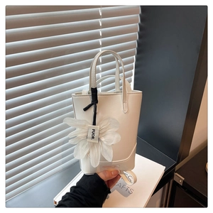 Detail of white bucket bag with large silk floral charm and leather texture