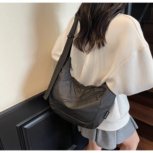 Close-up of black nylon dumpling bag with dual zipper detail and adjustable strap