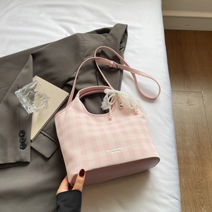 Détail du sac à main à carreaux roses avec nœud en dentelle blanche et perles décoratives