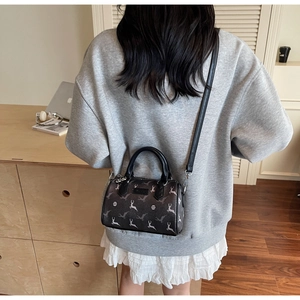 Sac bandoulière style Boston avec motif d'élan blanc porté par un mannequin en décor