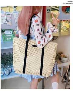 Detail view of woven tote bag with large hollow pattern and black shoulder straps