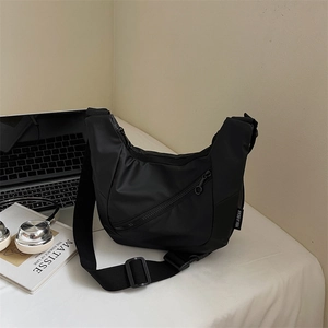 Close-up of black nylon crescent bag with adjustable strap and zip pocket detail