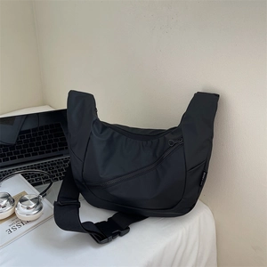 Detail of black nylon crossbody bag with adjustable buckle strap and zipper pocket