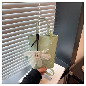Detail of mint green tote bag with white floral charm and printed leather branding