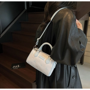 Sac Boston chic à imprimé animal bleu porté avec un manteau noir dans un escalier