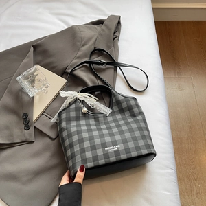 Détail du sac cabas à carreaux avec ruban en dentelle, perles et pendentif cœur