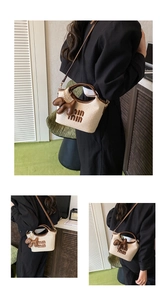 Close-up of woven straw handbag with brown leather handles and a cute puppy charm