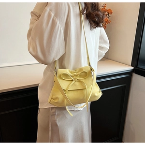 Detail of light yellow ballet style bow crossbody bag with fine synthetic leather texture