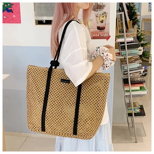 Detailed texture of straw woven tote bag with black rope handles and minimalist design