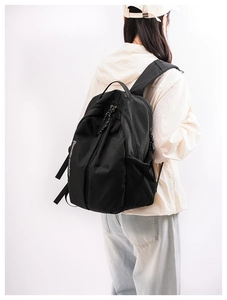 Detail of black outdoor backpack with side lettering and mesh pocket on white background
