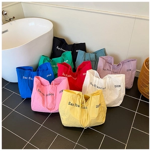 Multiple colorful nylon tote bags with San Francisco print displayed in a modern bathroom