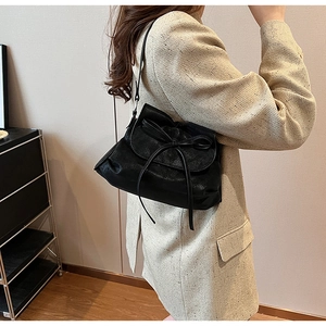 Detail of black leather hobo bag with bow drawstring and natural lychee grain texture