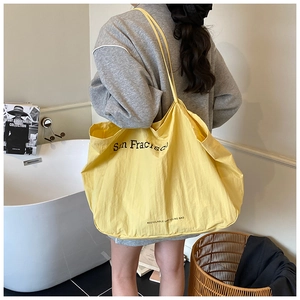 Detail view of yellow canvas tote bag with San Francisco text and eco-friendly recycle label