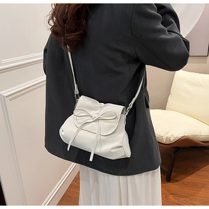 Detail of white PU leather crossbody bag with bow tie decoration on model's back
