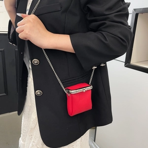 Mini red pebble leather lipstick bag with silver chain worn by model over black blazer