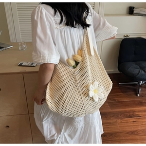 Detail of hollow knit shoulder bag with 3D white daisy and wide strap in warm indoor setting