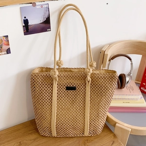 Close-up of beige woven tote bag with hollow grid pattern and black leather patch