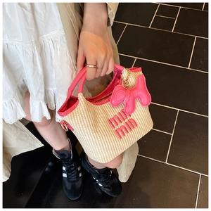 Detail of woven straw bag with pink leather handles and branded logo lettering