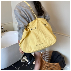 Detail of a large yellow recyclable tote bag showing material texture and shoulder fit