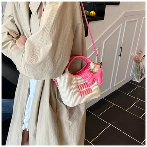 Detail of straw woven bucket bag with pink leather trim and cute puppy charm on model