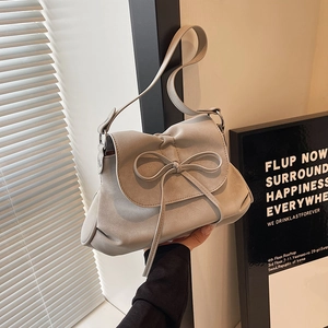 Detail of light grey leather shoulder bag with a bow tie and soft pleated base