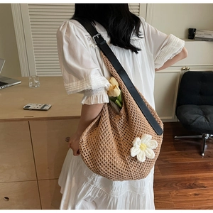 Hobo bag with crochet flower patterns and black leather strap in a minimalist setting