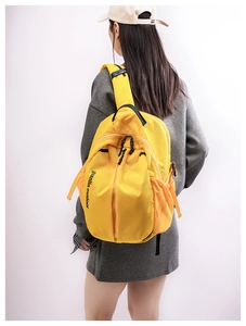 Rear view of a model wearing a large bright yellow outdoor backpack with side mesh pockets