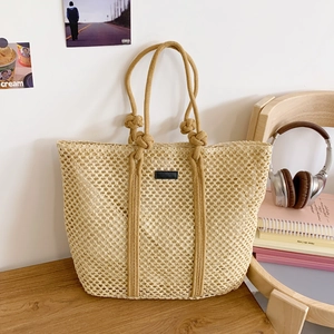 Detail of beige woven tote bag with hollow mesh design and decorative knot handle