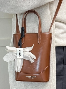 Minimalist brown oil wax leather tote bag with a white flower charm accessory