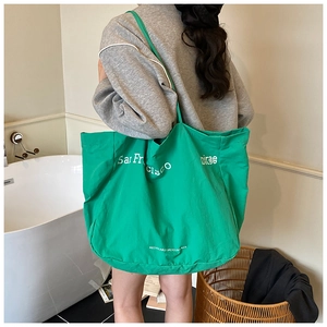 Detail of green canvas tote bag with San Francisco print worn by model in a minimal room
