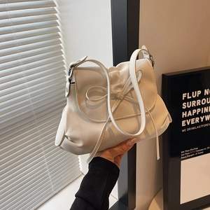 Detail of a chic cream white bucket bag with bow tie fold design and thin shoulder strap