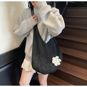 Close-up of black crochet shoulder bag with white daisy detail and leather strap