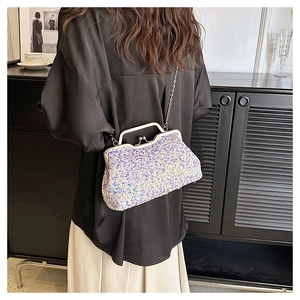 Detail of lavender sequin clutch bag with silver chain strap worn by a model