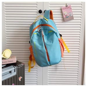 Close-up of sky blue nylon backpack with orange zippers and yellow strap accents
