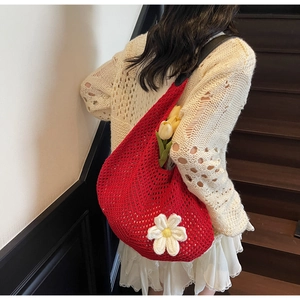 Detail of red hollow knit shoulder bag with white flower accent on beige sweater
