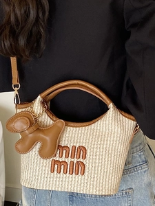 Minimalist straw tote bag with brown leather trim and shoulder strap in street style