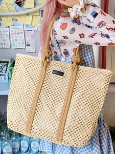 Large beige woven tote bag with rope handles and knot detail for summer beach vacations
