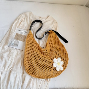 Detail of yellow hand-crocheted hollow bag with white daisy decor and black leather strap