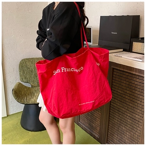 Detail of red canvas tote bag with San Francisco text being worn over the shoulder