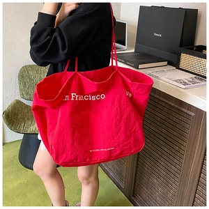 Detail of red San Francisco canvas tote bag showing large capacity and shoulder strap