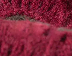 Macro di tessuto a maglia rosso scuro che mostra la consistenza morbida della lana