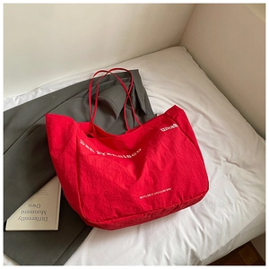 Detail view of red oversized tote bag with San Francisco print on a cozy bed background