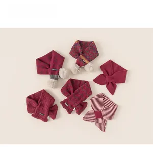 Dettaglio di diverse sciarpe lavorate a maglia bordeaux per bambini con fiocchi e pompon