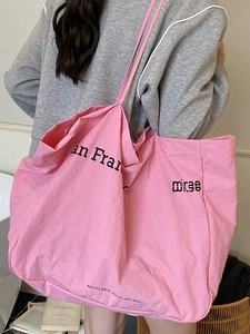 Pink oversized canvas tote bag made of recyclable materials shown in a lifestyle indoor setting