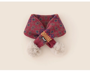 Dettaglio di sciarpa bordeaux a maglia con motivi floreali e morbidi pompon