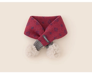 Dettaglio sciarpa in maglia rossa per bambini con rombi blu, coste grigie e pompon bianchi