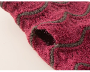 Dettaglio macro di sciarpa in maglia spessa con motivo a onde magenta e grigio