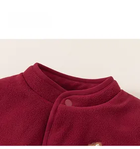Détail du tissu polaire bordeaux avec boutons-pression et broderie pour enfants