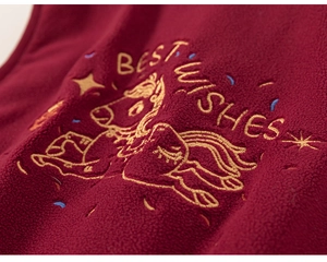 Vue macro du tissu polaire bordeaux avec broderie de cheval jaune et texte Best Wishes