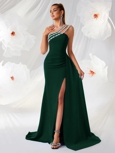 Détail d'une robe de soirée verte à une épaule avec garniture en strass et plis élégants